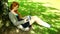 Gorgeous redhead typing on notebook leaning against tree