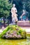 Gorgeous rocky stone fountain with sculpture of a woman surrounded by growing plants in Park Borghese in Rome, Italy