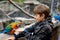 Gorgeous school kid boy feeding parrots in zoological garden. Child playing and feed trusting friendly birds in zoo and