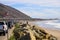 A gorgeous shot of the beach along the coast with vast blue ocean water, large rocks along the beach, silky sand with blue sky