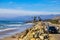 A gorgeous shot of the beach near a long stretch of road with cars and large rocks along the beach, vast blue ocean water