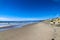 A gorgeous shot of the beach near a long stretch of road with cars and large rocks along the beach, vast blue ocean water