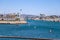 A gorgeous shot of boats and yachts docked in the harbor surrounded by vast deep blue ocean water, buildings and palm trees