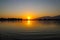 A gorgeous shot of a lake with rippling water at sunset with lush green trees and mountain ranges at Santa Fe Dam