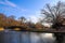 A gorgeous shot of a lake with a water fountain in the park near an arched cobble stone bridge