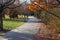 A gorgeous shot of a long smooth winding footpath in the park surrounded by gorgeous autumn colored trees with blue sky and clouds