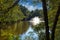 A gorgeous shot of a majestic water fountain in the middle of still lake water with lush green and autumn colored trees and plants