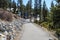 A gorgeous shot of a man walking down a smooth pathed hiking trail near the vast blue lake water