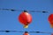 A gorgeous shot of rows of red Chinese lanterns hanging from black cables with a blue sky background at Atlantic Station