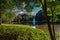 A gorgeous shot of the silky green lake water with a fountain in the middle of the lake with a stone bridge