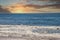 A gorgeous shot of the vast blue ocean water at sunset with waves rolling into the silky brown sand at Rincon Beach