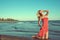 Gorgeous slim blond model in red strapless dress standing on knees in the sea water