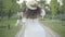 Gorgeous slim Middle Eastern woman in white dress and straw hat spinning as strolling along sunny summer alley in park