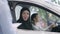 Gorgeous slim woman in hijab talking to unrecognizable dealer with blurred girl sitting on driver\'s seat at background