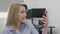 Gorgeous smiling businesswoman making video call using smartphone at office saying hello to webcam -