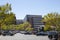 A gorgeous spring landscape in the city with office buildings, lush green trees and cars parked in a parking lot