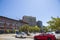 A gorgeous spring landscape in the city with office buildings, lush green trees and cars parked in a parking lot