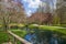 A gorgeous spring landscape in the garden with ponds surrounded by footpaths and lush green trees and grass, red trees