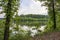 a gorgeous spring landscape at Proctor Landing Park at sunset with rippling water, lush green trees and plants, blue sky