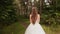 Gorgeous stylish bride in a vintage white dress, walking in the forest. Rear view.