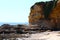 A gorgeous summer landscape on the beach with large rock formations covered in lush green plants surrounded by blue ocean water