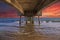 A gorgeous summer landscape at the beach under the Belmont Veterans Memorial Pier with blue ocean water and waves