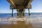 A gorgeous summer landscape at the beach under the Belmont Veterans Memorial Pier with blue ocean water and waves