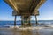 A gorgeous summer landscape at the beach under the Belmont Veterans Memorial Pier with blue ocean water and waves