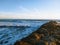 A gorgeous sunset on the beach with ocean waves rolling in and crashing into a jetty made of large rocks at Marina Park Beach