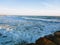 A gorgeous sunset on the beach with ocean waves rolling in and crashing into a jetty made of large rocks at Marina Park Beach