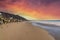 A gorgeous sunset at the beach with smooth silky sand and rocks along the beach with majestic mountains near by at Rincon Beach
