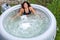 Gorgeous teenage girl with long, dark hair relaxes in the garden inflatable pool with jacuzzi