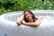 Gorgeous teenage girl with long, dark hair relaxes in the garden inflatable pool with jacuzzi