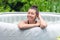 Gorgeous teenage girl with long, dark hair relaxes in the garden inflatable pool with jacuzzi