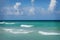 Gorgeous turquoise colored waters against a blue sky with white clouds on Hollywood Beach, Florida.