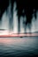 Gorgeous vertical shot of a dark blue-red sunset at sea with a boat on the horizon