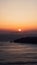 Gorgeous vertical shot of a golden sun over the horizon in Santorini, Greece at sunset