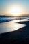 Gorgeous vertical shot of the silhouette of a person facing the low sea tide at sunrise