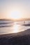 Gorgeous vertical shot of the silhouette of a woman facing the high sea tide at sunrise