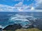 Gorgeous view from above of coral reefs and the movement of waves. Crystal clear water contrasts with dark volcanic rocks