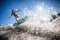 Gorgeous view of athlete woman in gray swimsuit who jumps with bright surf board.
