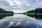 Gorgeous view of beautiful sky reflecting on a mirror of lake surface. Green forest trees bordering the lake on both size.