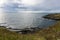 Gorgeous view of the grassy, rocky coastline on San Juan Island on a bright, sunny day with puffy white clouds