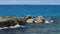 Gorgeous view of waves breaking on stones. Turquoise water of Atlantic ocean and big rocks on blue sky background. Wi