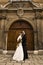 Gorgeous wedding couple bride and groom standing on staircase in front of historical church doorway and smiling