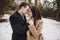 Gorgeous wedding couple hugging in winter snowy park. stylish bride in coat and  groom embracing under  trees in winter forest.