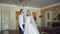 Gorgeous wedding couple kisses with smile in luxurious bedroom