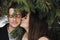 Gorgeous wedding couple kissing in winter snowy park. stylish bride in coat and  groom embracing under green trees in winter