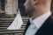 Gorgeous wedding couple posing on stone stairs near old castle in park. Stylish beautiful bride in amazing gown looking at groom