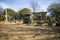 A gorgeous winter landscape in the graveyard with headstones, graves, bare winter trees, lush green trees, plants with flowers